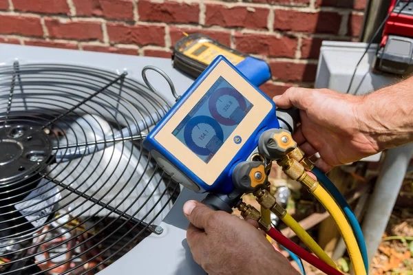 Digital manifold gauges connected to an outdoor HVAC unit